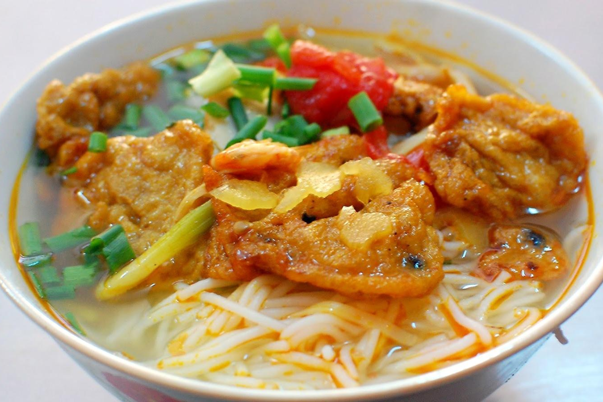 A bowl of grilled fish cake noodles with fresh greens
